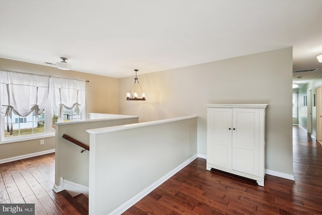 interior space with dark wood-type flooring, white cabinetry, hanging light fixtures, kitchen peninsula, and a notable chandelier