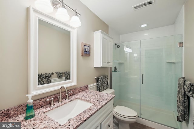 bathroom with toilet, a shower with shower door, and vanity