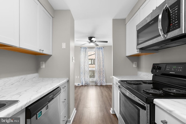 kitchen with white cabinetry, light stone counters, dark hardwood / wood-style flooring, ceiling fan, and stainless steel appliances