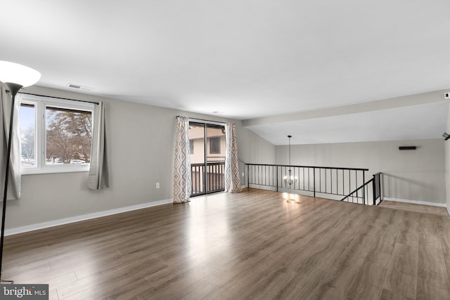 empty room with lofted ceiling, a notable chandelier, and dark wood-type flooring