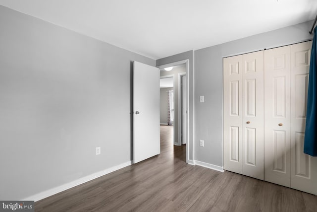 unfurnished bedroom with wood-type flooring and a closet