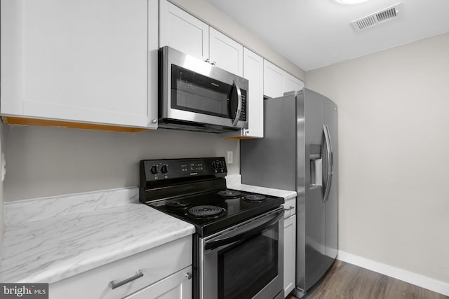 kitchen featuring dark wood-type flooring, appliances with stainless steel finishes, and white cabinets