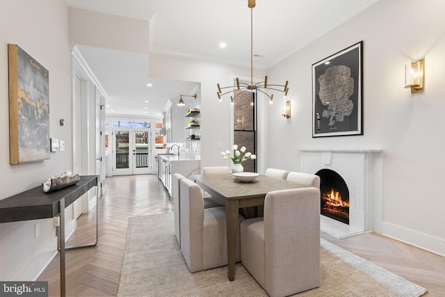 dining room with crown molding, light parquet flooring, sink, and french doors