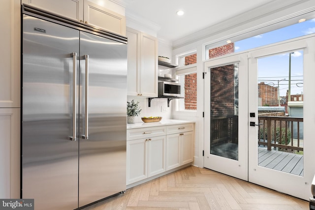 kitchen with french doors, light parquet flooring, appliances with stainless steel finishes, and ornamental molding