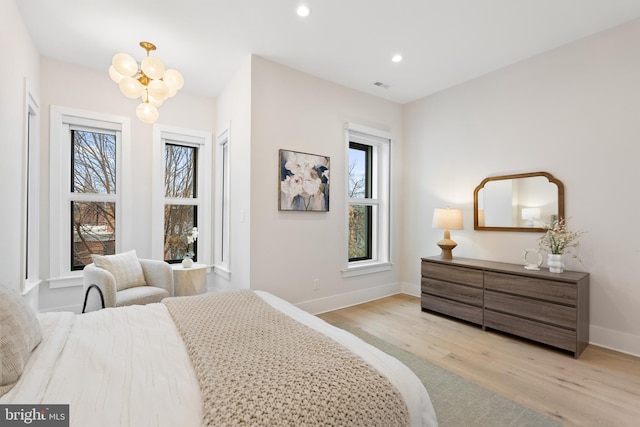 bedroom featuring an inviting chandelier and light hardwood / wood-style flooring