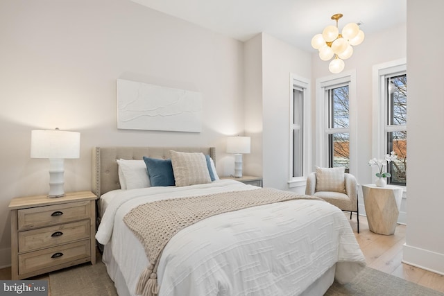 bedroom featuring an inviting chandelier and light hardwood / wood-style floors