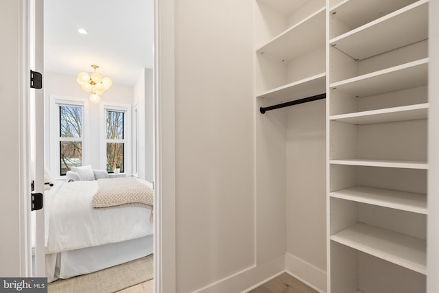 walk in closet featuring hardwood / wood-style flooring and a chandelier