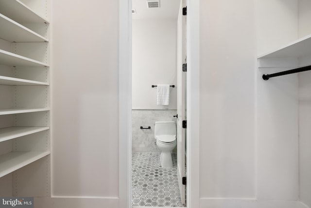 bathroom featuring tile walls and toilet