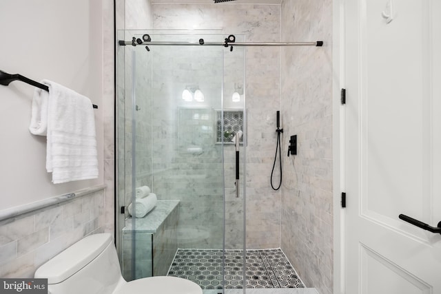 bathroom featuring a shower with door and toilet