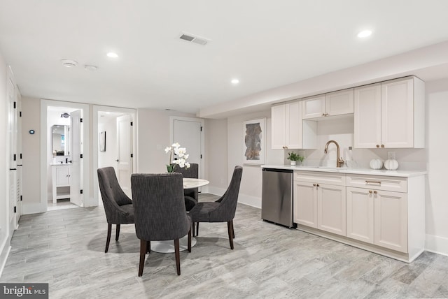 kitchen with sink, stainless steel dishwasher, white cabinets, and light wood-type flooring