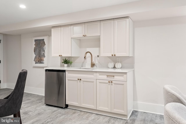 kitchen with white cabinetry, sink, stainless steel dishwasher, and light hardwood / wood-style floors