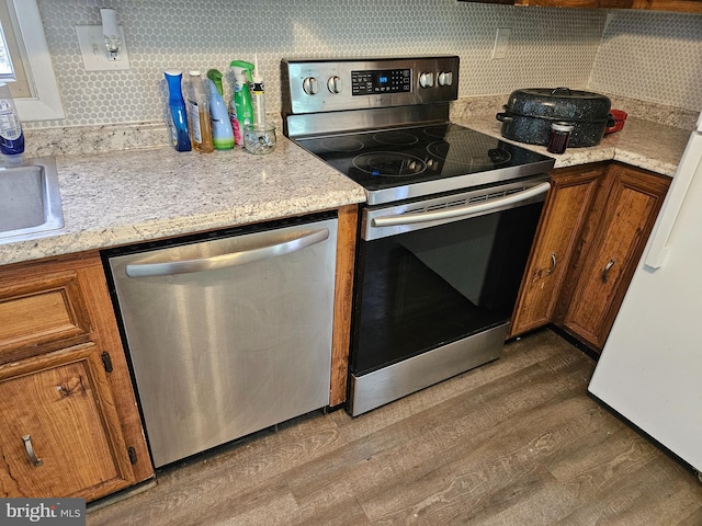 kitchen featuring light stone countertops, hardwood / wood-style floors, stainless steel appliances, and sink