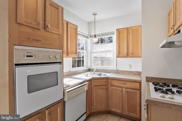 kitchen featuring light tile patterned flooring, white appliances, hanging light fixtures, and sink