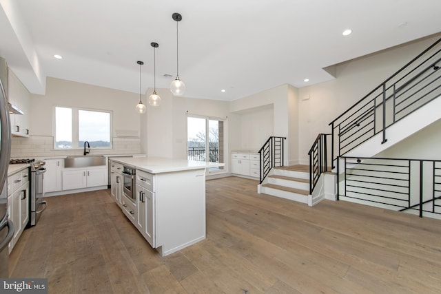 kitchen with a center island, decorative backsplash, white cabinets, appliances with stainless steel finishes, and sink