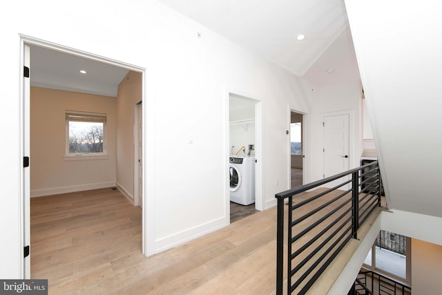 hallway with lofted ceiling, washing machine and clothes dryer, and light hardwood / wood-style floors