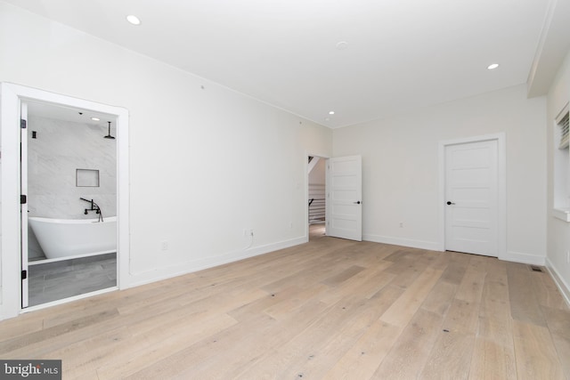 unfurnished bedroom featuring light hardwood / wood-style flooring and connected bathroom