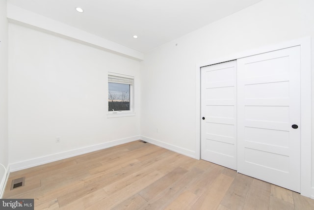 unfurnished bedroom with a closet and light wood-type flooring