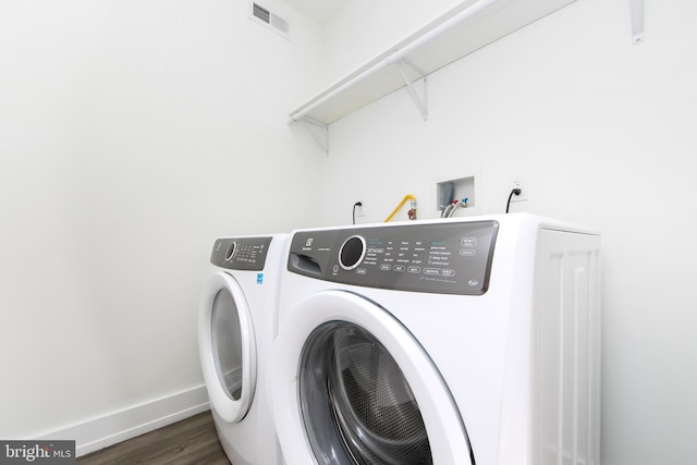 clothes washing area featuring dark wood-type flooring and washing machine and dryer