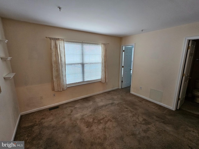 spare room with dark colored carpet