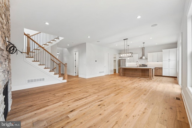 unfurnished living room with sink, a fireplace, and light wood-type flooring