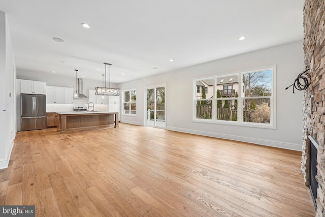 unfurnished living room featuring a stone fireplace, light wood-type flooring, and sink