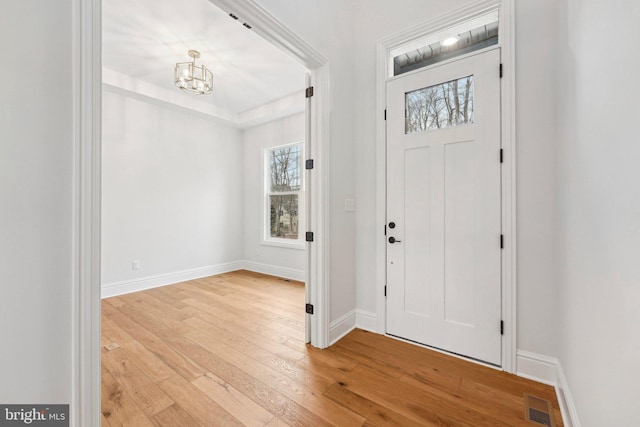 entryway with light hardwood / wood-style flooring, a healthy amount of sunlight, and a notable chandelier