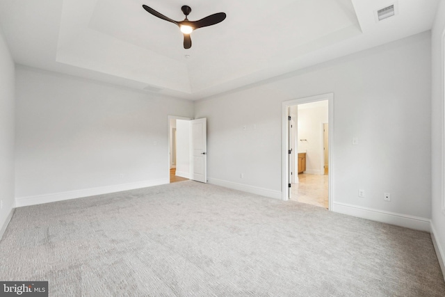 unfurnished bedroom featuring carpet, a tray ceiling, and ceiling fan