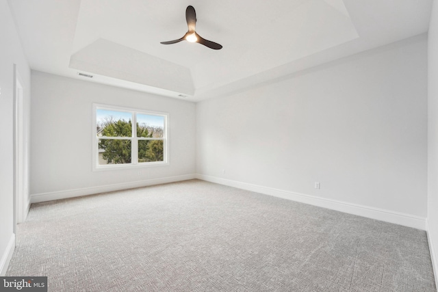 carpeted empty room with a tray ceiling and ceiling fan