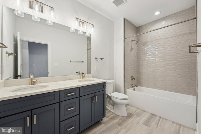 full bathroom with hardwood / wood-style floors, vanity, toilet, and tiled shower / bath