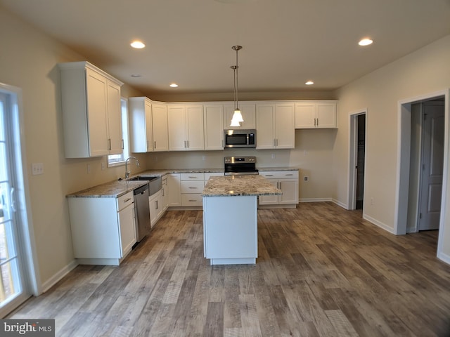 kitchen with a center island, white cabinetry, hanging light fixtures, and appliances with stainless steel finishes