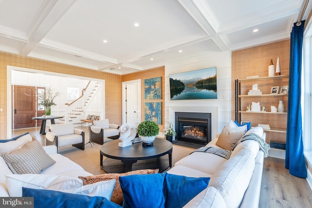 living room featuring beamed ceiling, light hardwood / wood-style flooring, a fireplace, and coffered ceiling