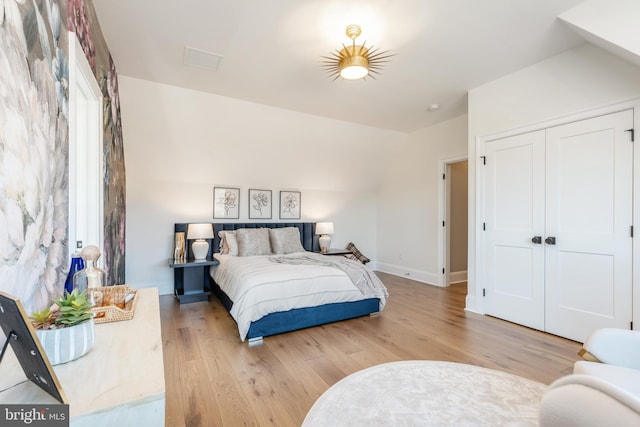 bedroom featuring light hardwood / wood-style floors, a closet, and lofted ceiling