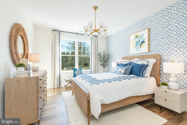 bedroom with light hardwood / wood-style flooring and an inviting chandelier