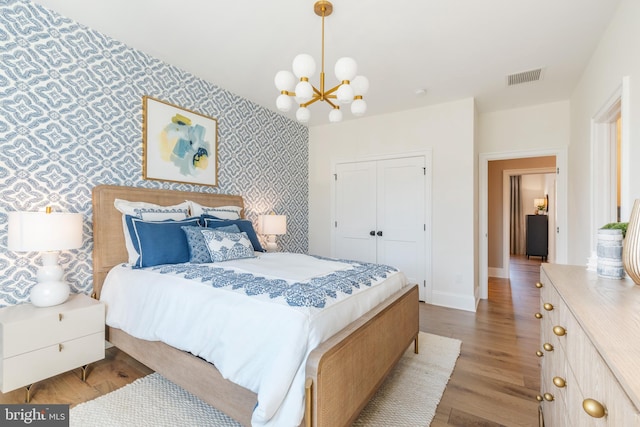 bedroom with light hardwood / wood-style flooring, a closet, and a notable chandelier