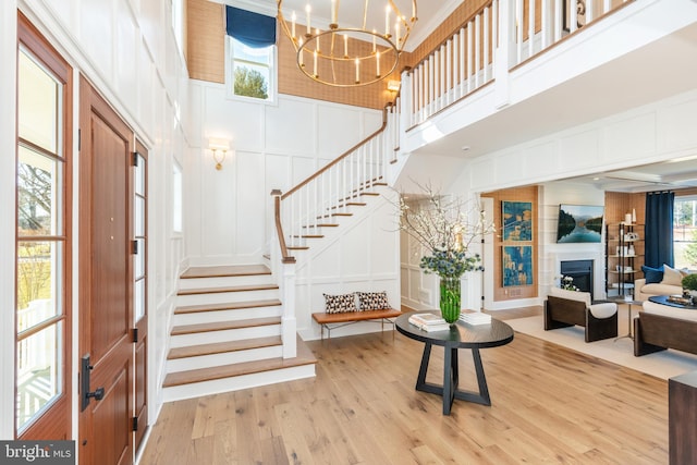 entrance foyer with crown molding, light hardwood / wood-style flooring, a towering ceiling, and an inviting chandelier