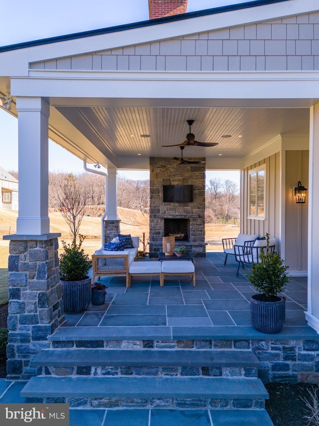 view of patio / terrace featuring an outdoor stone fireplace and ceiling fan