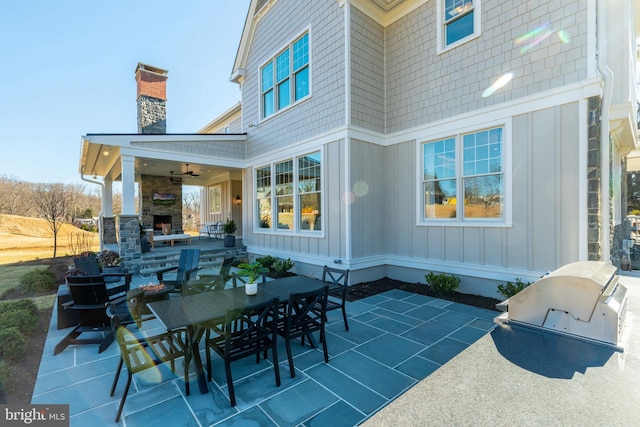 view of patio / terrace featuring an outdoor stone fireplace, ceiling fan, and exterior kitchen