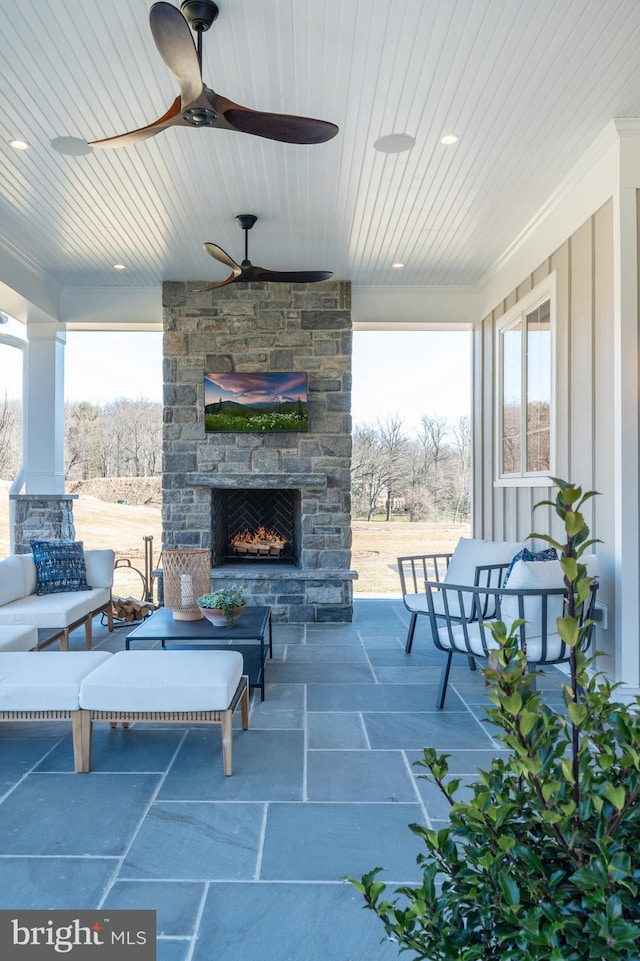 view of patio featuring an outdoor stone fireplace and ceiling fan