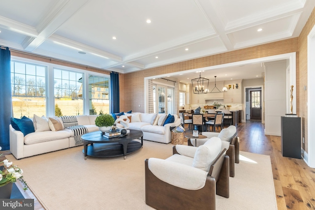 living room with beam ceiling, light hardwood / wood-style flooring, coffered ceiling, and an inviting chandelier