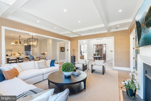 living room featuring coffered ceiling, crown molding, beam ceiling, an inviting chandelier, and light hardwood / wood-style floors