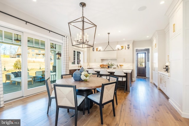 dining area featuring light wood-type flooring, a wealth of natural light, and a notable chandelier