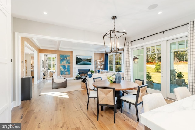 dining room featuring light hardwood / wood-style flooring, beamed ceiling, and an inviting chandelier