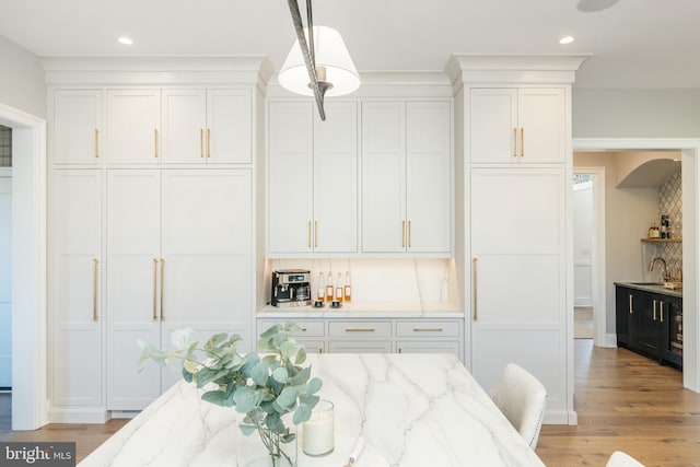 interior space with light stone countertops, pendant lighting, tasteful backsplash, and white cabinets