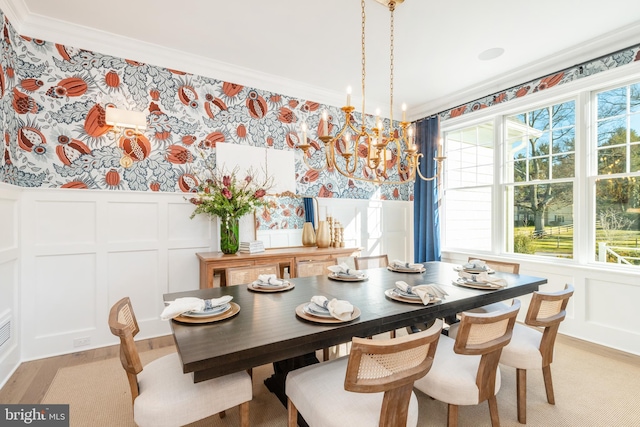 dining area with light hardwood / wood-style floors, an inviting chandelier, and ornamental molding