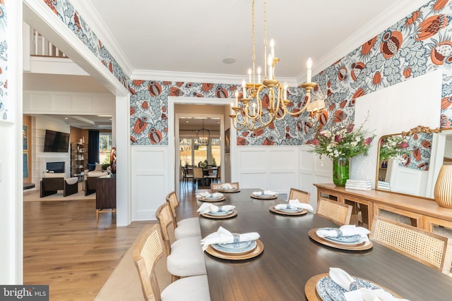 dining area with hardwood / wood-style floors, crown molding, and a notable chandelier