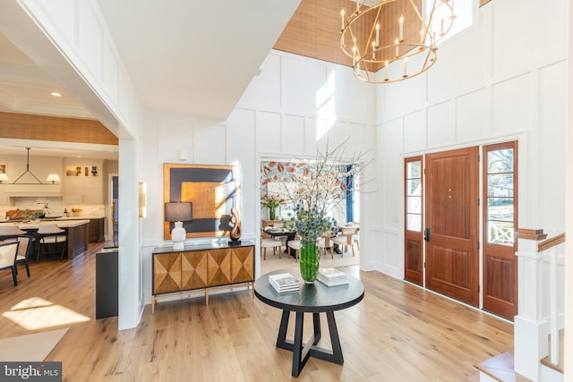 entryway with a high ceiling, light wood-type flooring, and a notable chandelier