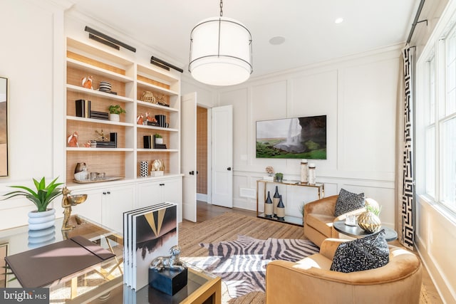 living room with light wood-type flooring, built in features, and ornamental molding