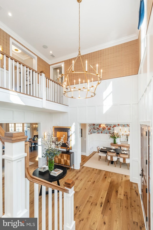 foyer with a towering ceiling, hardwood / wood-style flooring, and crown molding