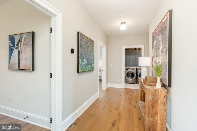 corridor with washing machine and dryer and light hardwood / wood-style flooring