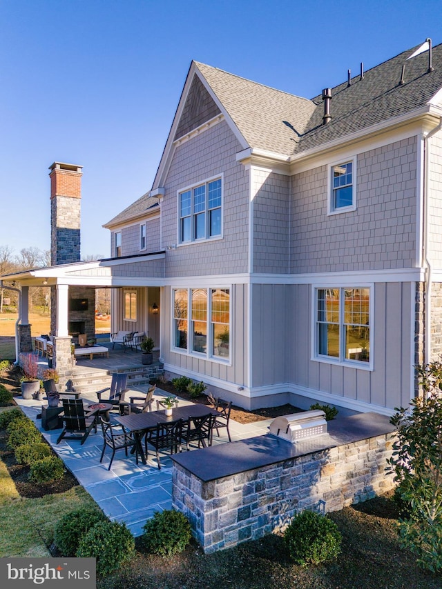 back of house featuring a patio area, a fireplace, and an outdoor kitchen